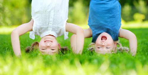 Happy children playing head over heels on green grass